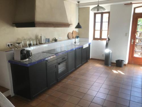 Il comprend une cuisine avec des placards noirs et du carrelage. dans l'établissement maison-michael, à Bédoin