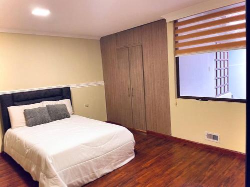 Un dormitorio con una cama blanca y una ventana. en Cerca de ToDo !, en Ambato
