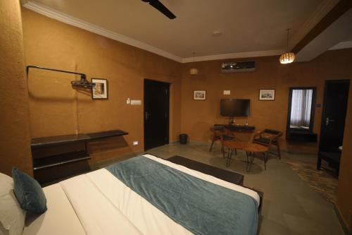 a bedroom with a bed and a desk and a table at Hotel Banjara Heritage in Udaipur