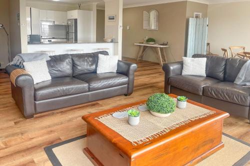 a living room with two leather couches and a table at Paradiso, 3,4 Laman Street - Comfortable unit with water views, aircon, solar heated pool and in the heart of town in Nelson Bay