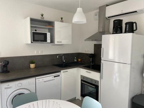 une cuisine avec des armoires blanches et un réfrigérateur blanc dans l'établissement T2 tout équipé à 300m de la plage, à Vias