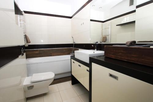 a bathroom with a white toilet and a sink at Apartment Classic Comfort in Elblag