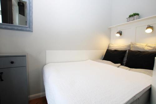 a small bedroom with a white bed and a mirror at Apartment Classic Comfort in Elblag