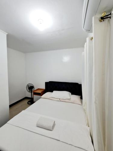 a white bed in a white room with a lamp at Calapan Transient Maple L82 in Calapan