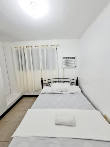 a white bedroom with a bed in a room at Calapan Transient Maple L82 in Calapan