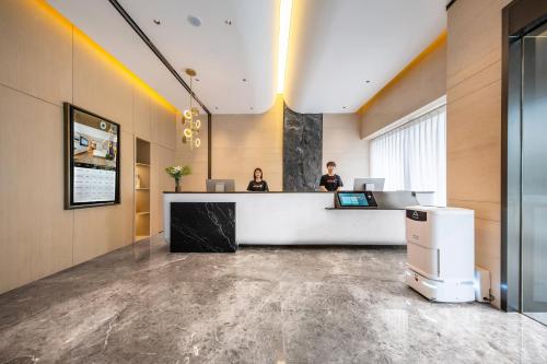 an office with two people standing at a reception desk at Atour Hotel Chengdu Phoenix Mountain Sports Park in Chengdu