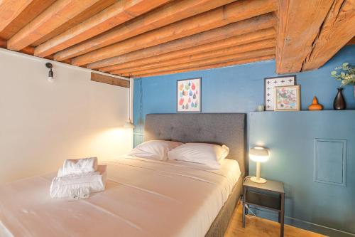 une chambre avec un lit blanc avec un mur bleu dans l'établissement Atypique et Cosy Hôtel de Ville et quais du Rhône, à Lyon