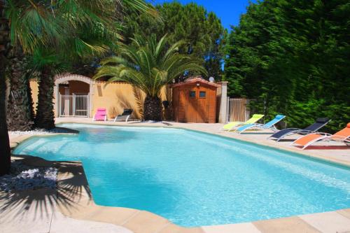 a swimming pool with lawn chairs and palm trees at L'Echappée Provençale - 4 Etoiles in Saint-Laurent-des-Arbres
