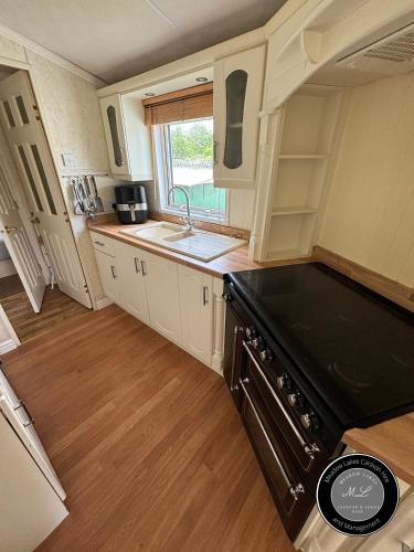 a kitchen with a sink and a stove at Parkside 41 - Located on Butlins Skegness Caravan Village, WiFi - Meadow Lakes Caravan & Lodge Hire in Lincolnshire