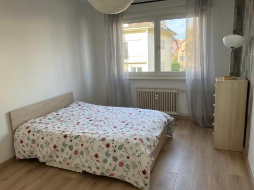 - une chambre avec un lit doté d'un couvre-lit floral et d'une fenêtre dans l'établissement Chez Gary, à Strasbourg
