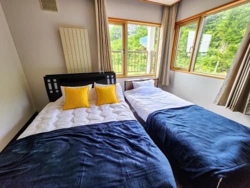 two beds sitting next to each other in a room with windows at Guest House ODAITO NEST in Odaitō