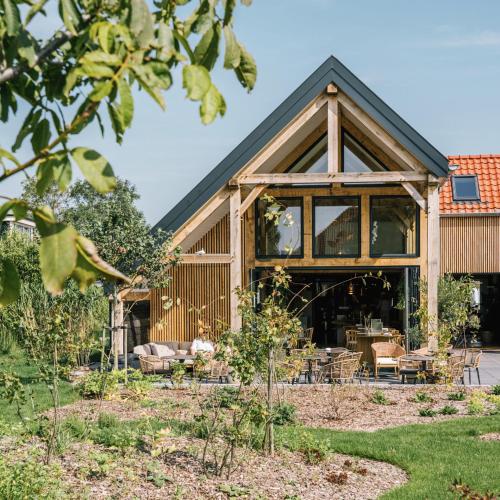 a house with a conservatory in a garden at Op Oost Boutique hotel & Restaurant het Kook Atelier in Oosterend