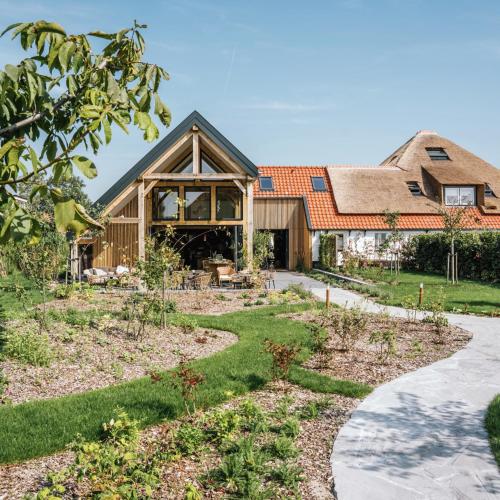 a house with a thatched roof and a garden at Op Oost Boutique hotel & Restaurant het Kook Atelier in Oosterend