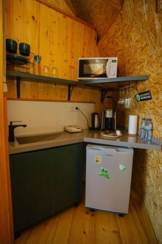 a small kitchen with a refrigerator and a microwave at Glamping Martini Kvariati with pool in Batumi