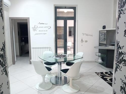 a dining room with a glass table and white chairs at Casa vacanze Emma Siracusa Canicattini Bagni in Canicattini Bagni