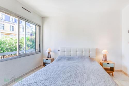 - une chambre blanche avec un grand lit et deux lampes dans l'établissement Appartement les pieds dans l'eau, à Saint-Raphaël