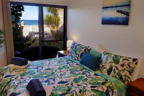 a bedroom with a bed with a view of the ocean at Homely Beachfront Apartment with Direct Beach Access - The Coachhouse in Narrabeen