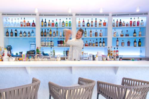 a woman standing behind a counter in a bar at Akoya Hotel & Spa in Saint-Gilles les Bains