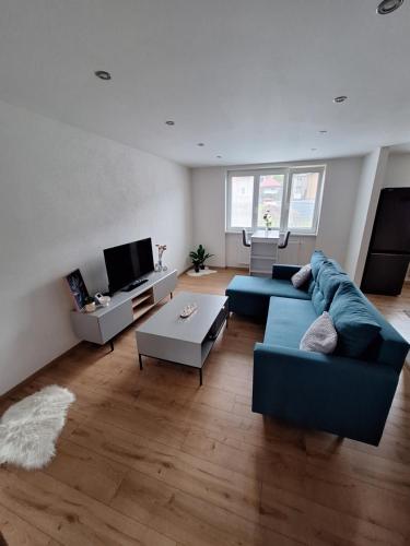 a living room with a blue couch and a tv at Farmársky apartmán Agrofarma Dianiška in Tisovec