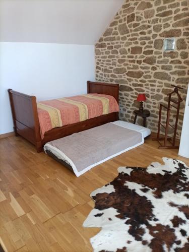 une chambre avec deux lits et un mur en pierre dans l'établissement La Rezendine, à Saint-Georges-de-Reintembault