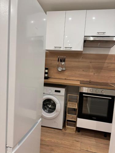 une cuisine avec des armoires blanches et une laveuse et une sécheuse dans l'établissement Superbes logements - Proche Stade de France et village olympique, à Saint-Denis