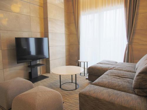 a living room with a couch and a flat screen tv at Hotel Regina Kawaguchiko in Fujikawaguchiko
