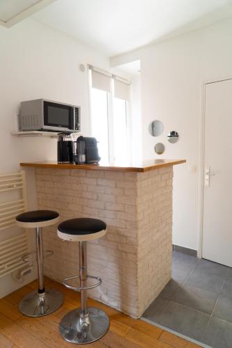 une cuisine avec un comptoir et deux tabourets dans l'établissement L'immersion - Super Studio - République - Paris, à Paris