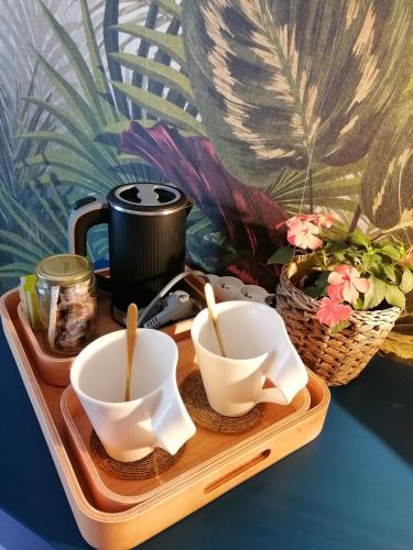 un plateau avec deux bols blancs et un pot et des fleurs dans l'établissement Chambre chez l habitant avec petit déjeuner, à Moussy-le-Vieux