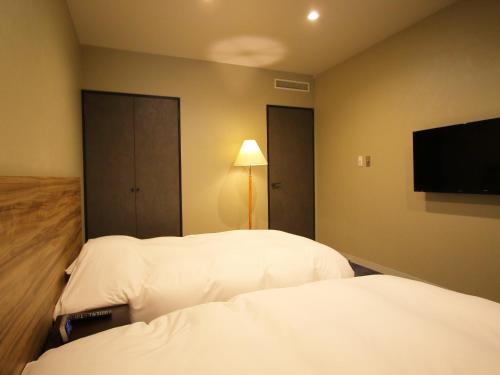 a hotel room with two beds and a flat screen tv at Hotel Regina Kawaguchiko in Fujikawaguchiko
