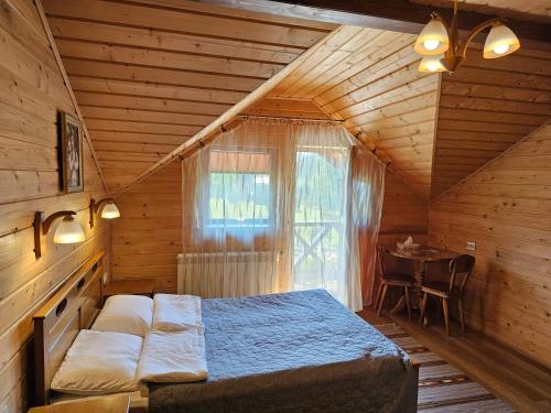a bedroom with a bed in a wooden room at Guesthouse Kolo Druziv in Tatariv