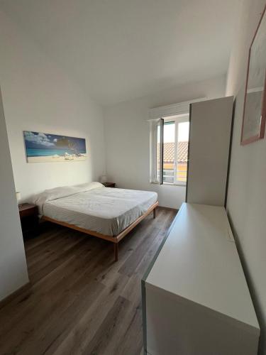 a white bedroom with a bed and a window at La casa di Pi in Montacuto