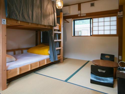 a room with bunk beds and a desk and a table at Next Chapter - Guesthouse - Kito in Uinouchi