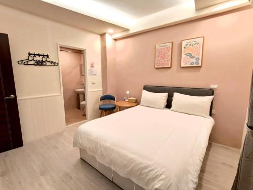 a bedroom with a white bed and a blue chair at 花蓮後站-沐青文旅 in Hualien City