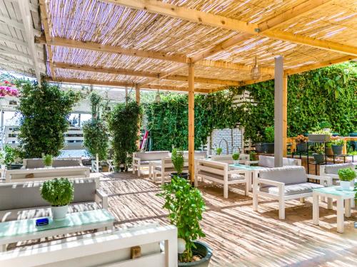a patio with tables and chairs and a wooden pergola at Epirus Hotel in Sarandë