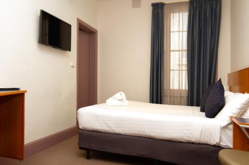 a hotel room with a bed and a flat screen tv at Central Hotel Hobart in Hobart