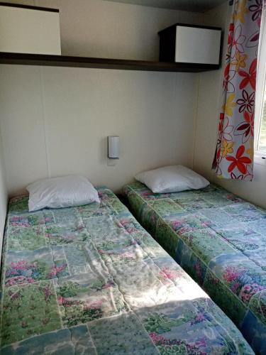 deux lits côte à côte dans une pièce dans l'établissement Mobil-home, à Beynes