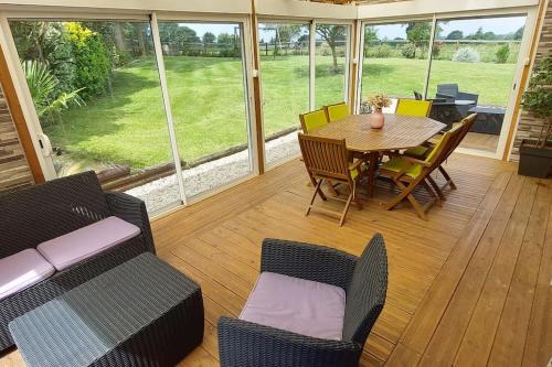 une véranda avec une table et des chaises dans l'établissement Maison proche Hauteville-sur-mer, à Le Grand Cambry