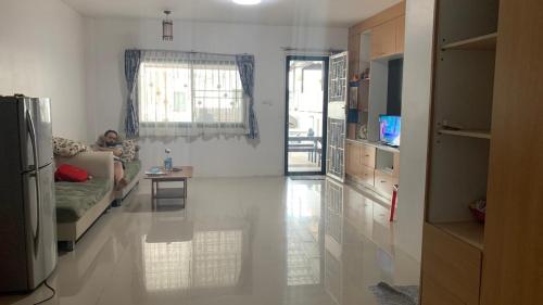 a man sitting on a couch in a living room at Min&Me House Pattaya in Nong Prue