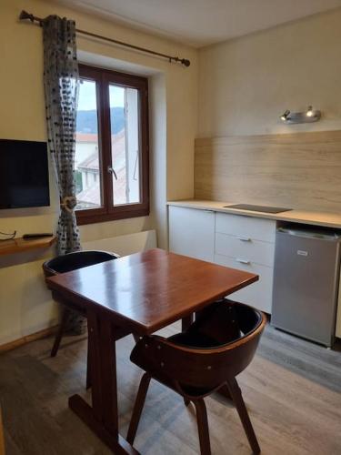 une cuisine avec une table en bois et deux chaises dans l'établissement Studio cosy - centre du village, à Autrans