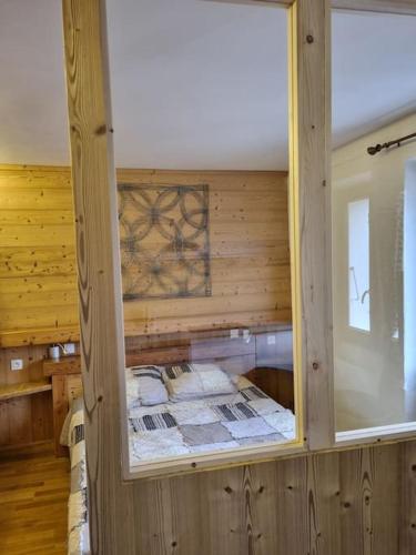 Cette chambre est dotée d'un mur en bois et d'une fenêtre. dans l'établissement Studio cosy - centre du village, à Autrans