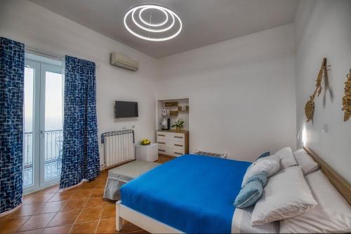 a bedroom with a blue bed and a large window at Salvo's House in Furore