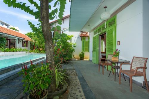 a patio with a table and chairs next to a pool at Hoi An Garden Villas in Hoi An