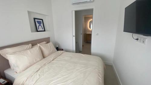 un lit avec des draps blancs et des oreillers dans une chambre dans l'établissement Appartement Rooftop Cannes, à Cannes