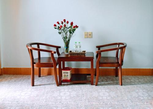 two chairs and a table with a vase of flowers at NHAT LE Hotel in Hue