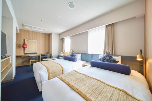 a hotel room with two beds and a desk at Meitetsu Inn Nagoya Kanayama Annex in Nagoya