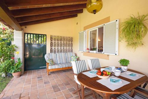 a patio with a wooden table and chairs and a window at Finca con piscina Es Baladre in Capdepera