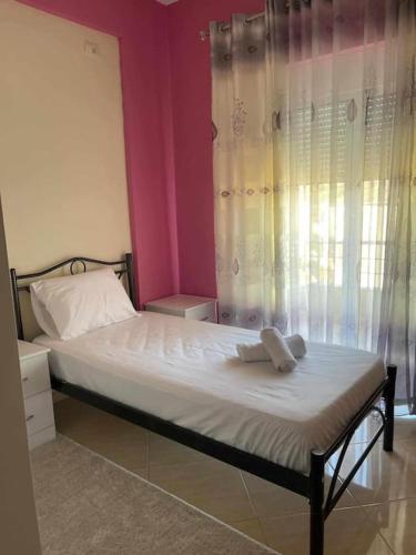a bedroom with a bed with white sheets and a window at Jonas Apartment in Gjirokastër