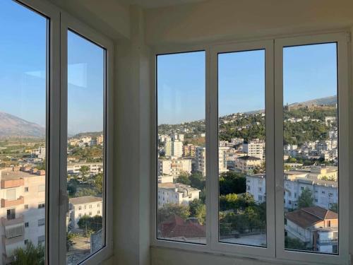 a room with three windows with a view of a city at Jonas Apartment in Gjirokastër