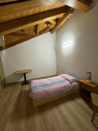 a bedroom with a bed and a table and wooden ceilings at B&B antico tabià dolomitico in Santo Stefano di Cadore
