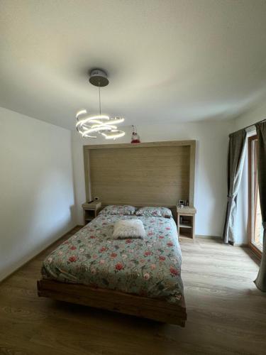 a bedroom with a bed and a chandelier at B&B antico tabià dolomitico in Santo Stefano di Cadore